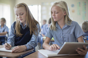 Zwei Schulmädchen im Klassenzimmer mit digitalem Tablet und Notizblock - ZEF004965