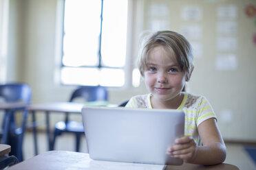 Portrait of smiling primary schoolgirl with digital tablet - ZEF004981