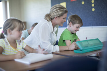 Teacher helping schoolboy in classroom - ZEF004988