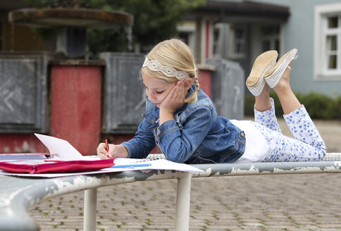 Little girl doing homework at school yard - WWF003625