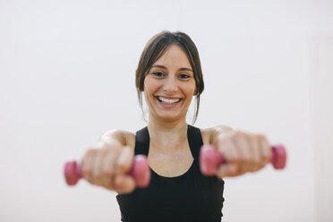 Portrait of smiling woman holding dumbbells - EBSF000430