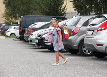 Little girl on her school way crossing parking area - WWF003670