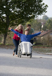 Junges Paar mit Freund im Rollstuhl sitzend - WWF003654