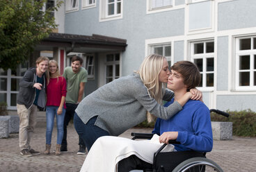 Junge Frau küsst ihren Freund im Rollstuhl sitzend - WWF003657