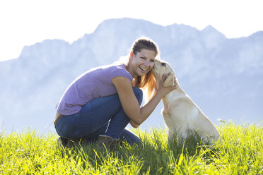 Austria, Mondsee, woman with Labrador Retriever on Alpine meadow - WWF003739