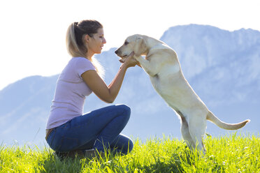 Österreich, Mondsee, Frau mit Labrador Retriever auf Almwiese - WWF003740