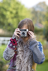 Young woman taking a picture of viewer with an old camera - WWF003889