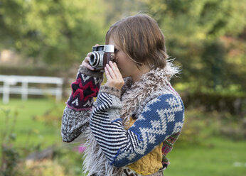 Junge Frau beim Fotografieren mit einer alten Kamera in der Natur - WWF003890