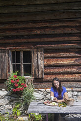 Österreich, Altenmarkt-Zauchensee, junge Frau bei der Arbeit auf einer Almhütte - HHF005070