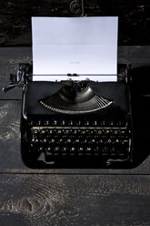 Alte schwarze Schreibmaschine auf dunklem Holz - MAEF009494