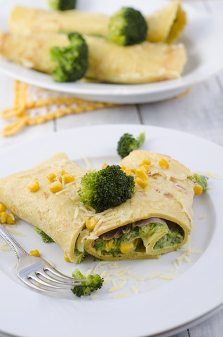 Gefüllter Pfannkuchen mit Brokkoli, Mais und geriebenem Käse auf Teller, lizenzfreies Stockfoto