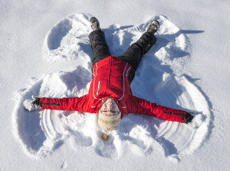 Austria, Tyrol, Pertisau, young woman making snow angel - MKFF000155