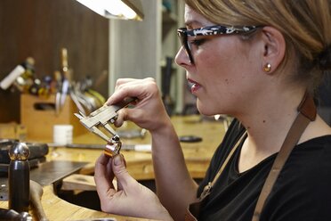 Goldschmied in der Werkstatt beim Messen eines Rings mit einem Messschieber - EDF000114