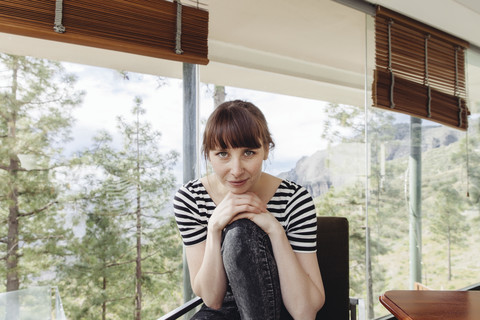 Frau posiert auf einem Stuhl vor einer Fensterscheibe, lizenzfreies Stockfoto