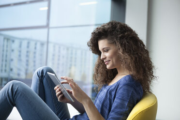 Smiling young woman using digital tablet at the window - RBF002312