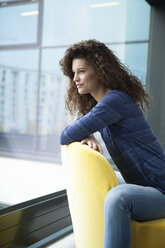 Smiling young woman looking out of window - RBF002313