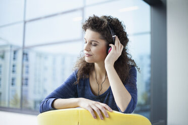 Young woman wearing headphones at the window - RBF002316