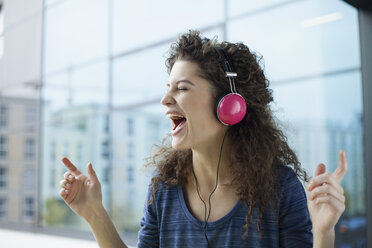 Screaming young woman wearing headphones at the window - RBF002317