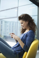 Young woman using cell phone at the window - RBF002318