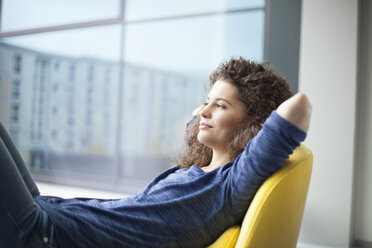 Smiling young woman looking out of window - RBF002319