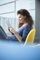 Smiling young woman using digital tablet at the window - RBF002328