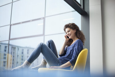 Lächelnde junge Frau beim Telefonieren am Fenster - RBF002332