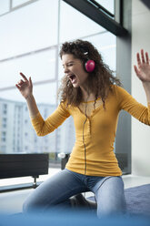 Screaming young woman wearing headphones at the window - RBF002310