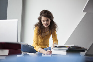 Studentin sitzt mit Büchern auf dem Boden - RBF002347