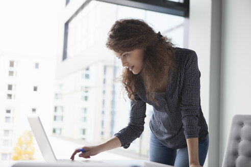 Young woman using laptop at desk in office - RBF002352