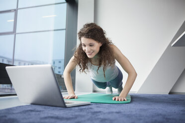 Frau beim Turnen mit Laptop - RBF002358