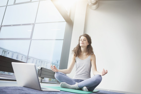 Frau beim Yoga mit Laptop, lizenzfreies Stockfoto