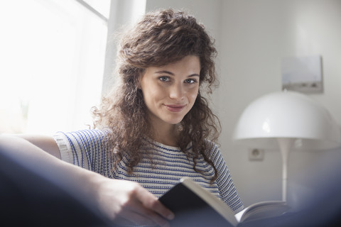 Porträt einer jungen Frau, die zu Hause ein Buch liest, lizenzfreies Stockfoto