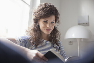 Porträt einer jungen Frau, die zu Hause ein Buch liest - RBF002290