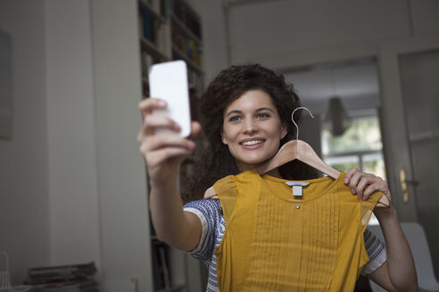 Young woman at home taking a selfie with piece of clothing - RBF002303