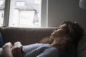 Serious young woman lying on sofa - RBF002261