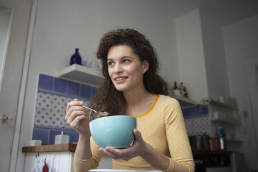 Young woman in kitchen holding cereal bowl - RBF002267