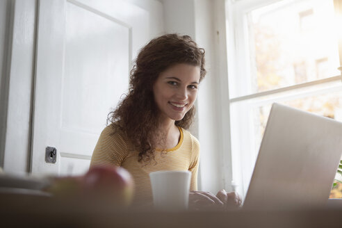 Lächelnde junge Frau zu Hause am Laptop - RBF002262