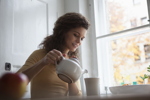 Young woman pouring tea into cup stock photo