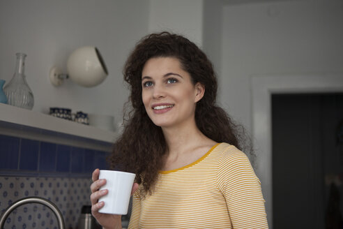 Smiling young woman holding cup - RBF002268