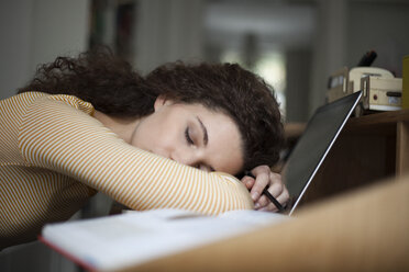 Overworked young woman sleeping on laptop in home office - RBF002273