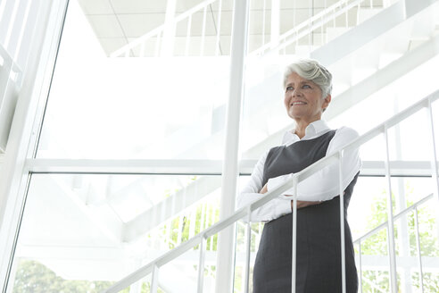 Smiling mature businesswoman on office staircase - MFRF000002