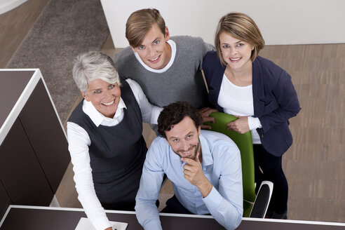 Smiling business team at desk in office - MFRF000015