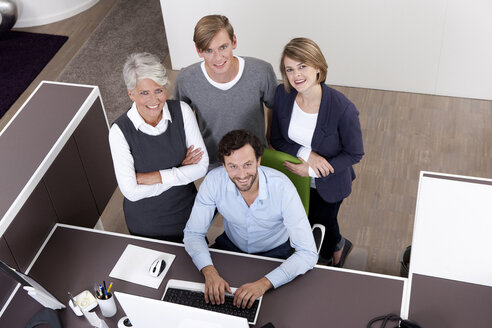 Lächelndes Geschäftsteam am Schreibtisch im Büro - MFRF000016