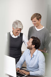 Smiling business team at desk in office - MFRF000060