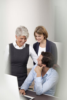 Smiling business team at desk in office - MFRF000019