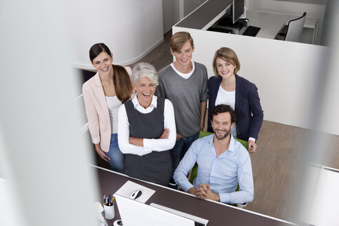 Happy business team at desk in office - MFRF000021