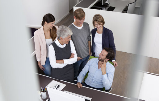 Happy business team at desk in office - MFRF000022