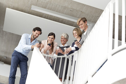 Businesspeople using cell phones in staircase - MFRF000055