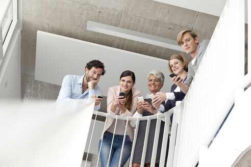 Businesspeople using cell phones in staircase - MFRF000056