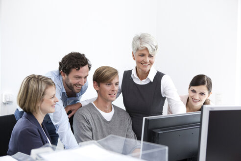 Smiling business team working on computer in office - MFRF000024